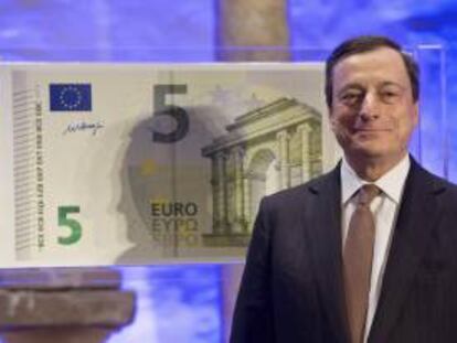 El presidente del Banco Central Europeo (BCE), Mario Draghi, posa al lado de una copia a tamaño gigante del nuevo billete de cinco euros, en Fráncfort, el 10 de enero de 2013. EFE/Archivo