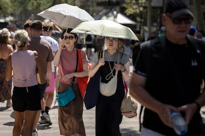 Turistas caminan por la Rambla de Barcelona en plena ola de calor.