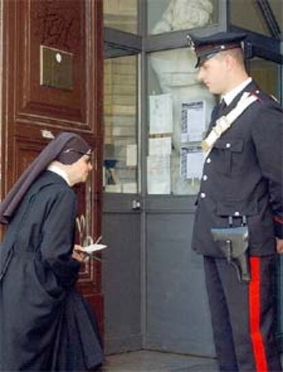 Una monja acude a votar en Roma ante la mirada de un <b><i>carabiniere.</b></i>