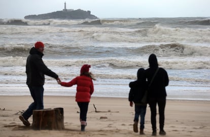 Una familia paseando un día de fuerte viento por la playa de Somo, en Cantabria. 