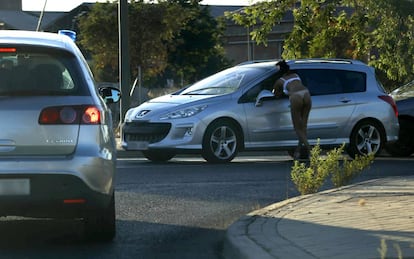 Una prostituta habla con un cliente en el polígono Marconi delante de un coche camuflado de la Policía Nacional.