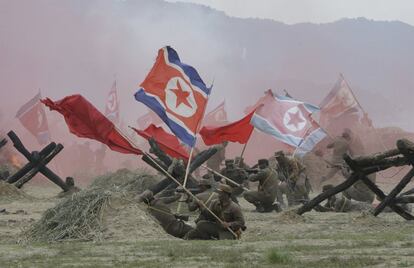 Soldados del ejército de Corea del Sur vestidos como soldados de Corea del Norte ondean banderas nacionales durante la reconstrucción de la Batalla del río Naktong en Waegwan (Corea del Sur).