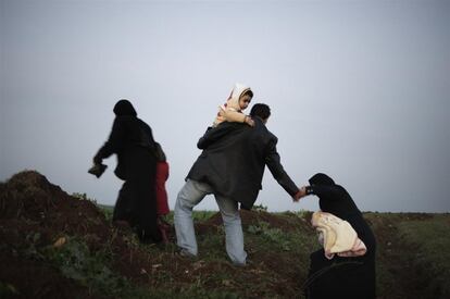 El 14 de abril de 2012, un hombre sostiene a un niño en su brazo izquierdo mientras extiende su mano derecha para ayudar a una mujer que lleva un bebé mientras ascienden una colina. Todos huían de la violencia en Siria, todos intentaban cruzar la frontera del país para refugiarse en la vecina Turquía. Para julio de 2012, en Siria, 1,5 millones de personas dentro del país necesitaban asistencia humanitaria. Los servicios de educación y salud se interrumpieron y la inseguridad alimentaria aumentó.