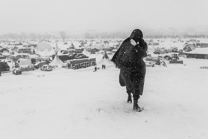 Una mujer camina por la nieve durante una ventisca.