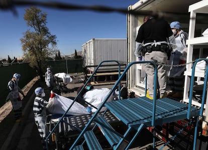 Reclusos del condado de El Paso trasladan los cuerpos a uno de los diez remolques refrigerados de la morgue temporal frente al edificio del anatómico forense. Los presos con condenas pequeñas se ofrecen como voluntarios para el trabajo y ganan dos dólares por hora. Texas superó las 20.000 muertes confirmadas por coronavirus hoy, la segunda más alta en Estados Unidos.