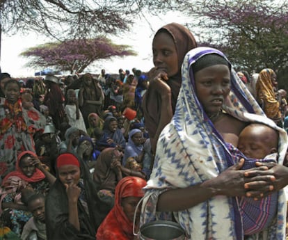 Mujeres y niños desplazados esperan para recibir comida en un campamento improvisado en Mogadiscio (Somalia).