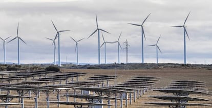 En primer plano, una planta solar y, al fondo, una eólica.