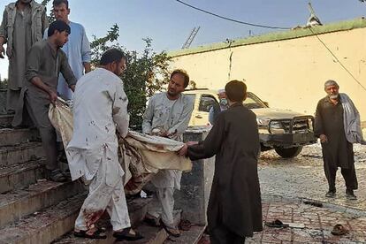 Un grupo de afganos cargan el cadáver de una víctima a una ambulancia tras el atentado.