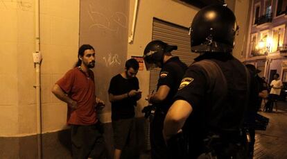 Dos agentes identifican a unos manifestantes tras la protesta ante la sede del PP en Valencia.