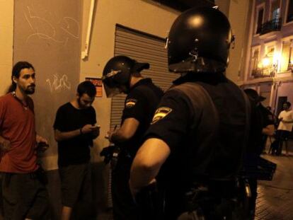 Dos agentes identifican a unos manifestantes tras la protesta ante la sede del PP en Valencia.