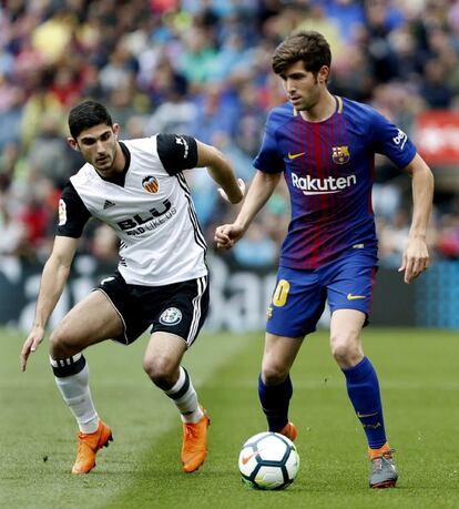 El centrocampista del Barcelona, Sergi Roberto (d), conduce el balón ante la presencia del centrocampista portugués del Valencia, Gonçalo Guedes (i).