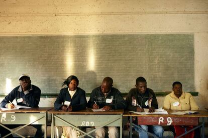 El personal electoral se sienta en una mesa de votación en el suburbio de Harare.