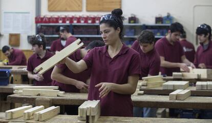 Diversos alumnes treballen la fusta al taller de l'Escola del Treball a Barcelona.