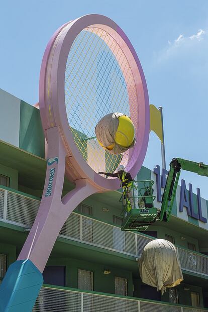 Un trabajador subido a
una grúa hace labores de
mantenimiento en una
raqueta de tenis gigante.
