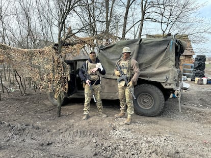 Los soldados ucranios Kotya y Sova con uno de los perros que vive con ellos en el frente de Robotine. 