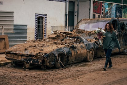 Cementerio de vehículos en las calles de Picaña. En la imagen, tomada el 15 de noviembre, una mujer pasa delante de un Pontiac Firebird Trans, réplica del famoso coche de la serie 'El coche fantástico'. 