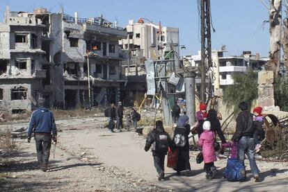 Civilians carry their belongings as they walk towards a meeting point to be evacuated from a besieged area of Homs February 9, 2014. Six hundred people left the besieged ruins of rebel-held central Homs on Sunday, escaping more than a year of hunger and deprivation caused by one of the most protracted blockades of Syria's devastating conflict. The evacuees, mainly women, children and old men, were brought out by the United Nations and Syrian Red Crescent on the third day of an operation during which the aid convoys came under fire and were briefly trapped themselves in the city. Picture taken February 9, 2014. REUTERS/Yazan Homsy (SYRIA - Tags: POLITICS CIVIL UNREST CONFLICT)