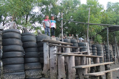 Un par de niños de la isla Punta Arenas posan desde la cima de una escalera de madera antes de que vuelva a subir la marea.