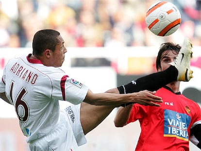 El jugador del Sevilla Adriano y el del Mallorca Pereyra durante el encuentro disputado hoy en el Sánchez Pizjuan.
