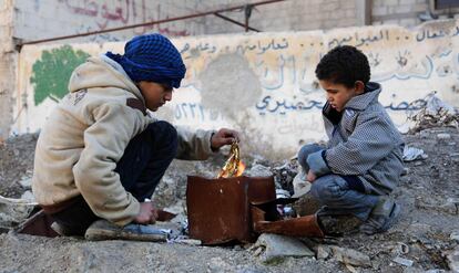 Dos niños hacen fuego en la zona rebelde de Kafr Batna a las afueras de Damasco (Siria).