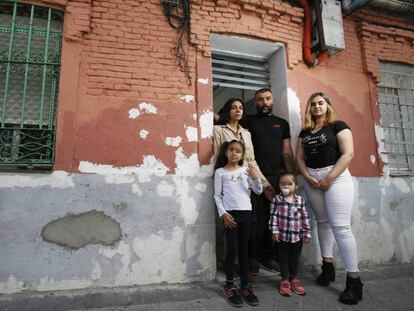 La familia, fotografiada frente a la puerta de su vivienda, en Vallecas. 