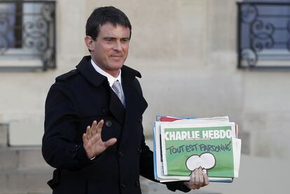El primer ministro francés, Manuel Valls, sostiene la nueva edición de la revista 'Charlie Hebdo' al salir de la reunión semanal del Gabinete en el palacio presidencial del Elíseo.