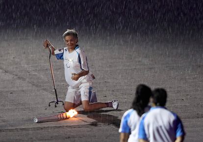 A atleta paraolímpica Marcia Malsar tropeça com a tocha olímpica a caminho da pira.