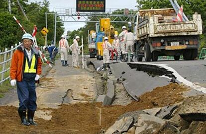 Un grupo de trabajadores inspecciona los daños causados en una carretera por el terromoto.