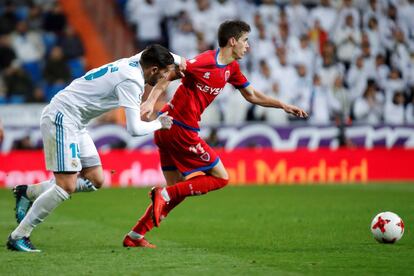 El centrocampista del Numancia, Ignacio Agustín Sánchez "Nacho", se lleva el balón ante el acoso del defensa francés del Real Madrid, Theo Hernández.