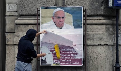 Un operario cubre un cartel contra el Papa en una calle de Roma.