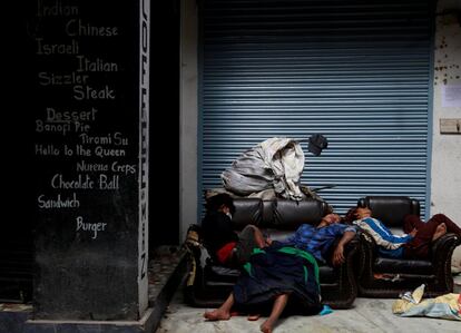 Un grupo de jóvenes duerme en un sofá abandonado en el exterior de una cafetería en Katmandú (Nepal) durante la pandemia que sufre el país.