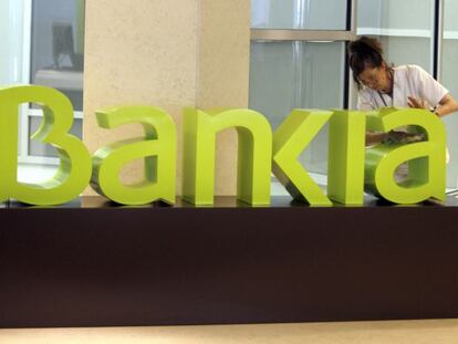 Una operaria limpia el logo de Bankia.