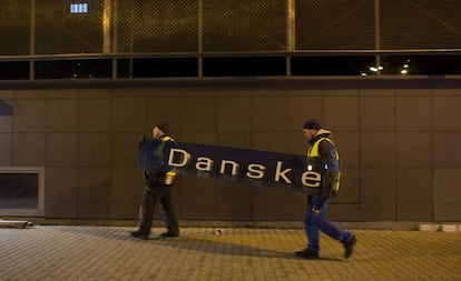 Dois operários retiram o cartaz do Danske Bank na filial de Tallin (Estônia), em 5 de outubro de 2019.