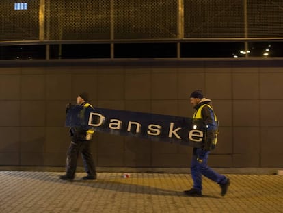 Dois operários retiram o cartaz do Danske Bank na filial de Tallin (Estônia), em 5 de outubro de 2019.