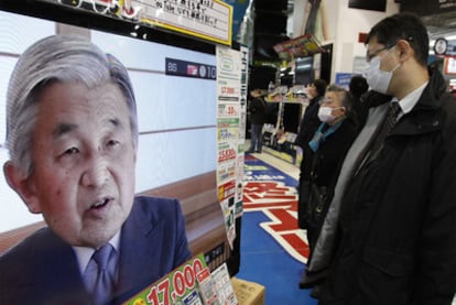 La clientela de una tienda de electrónica en Tokio escucha el discurso del emperador.