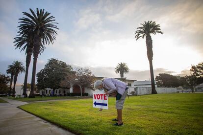 Una mujer pone carteles para votar antes de que abra el centro de votación de la biblioteca de Main Street Branch en Huntington Beach, California.