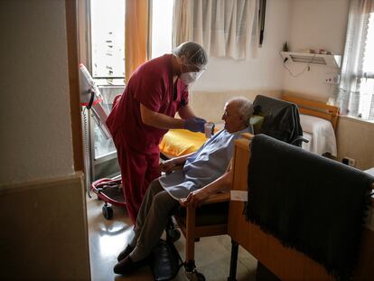 Un empleado le da líquido a un hombre mayor en una de las habitaciones en la Residencia de ancianos Santa María de Montecarmelo en Madrid, el pasado abril.