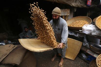 Un trabajador prepara cacahuetes para su venta en un mercado de frutos secos en Peshawar (Pakistán).