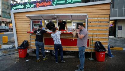 Tres iraqu&iacute;es junto a un restaurante callejero de Bagdad.