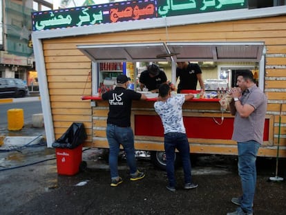 Tres iraqu&iacute;es junto a un restaurante callejero de Bagdad.