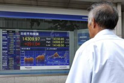 Un viandante pasa delante de una pantalla que muestra el valor del índice Nikkei. EFE/Archivo