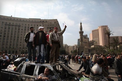 Manifestantes se encaraman a lo alto de unos coches quemados en la plaza Tahrir (Liberación) de El Cairo.