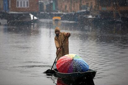 Un hombre rema su barco en las aguas del lago Dal durante una nevada en Srinagar (Cachemira).