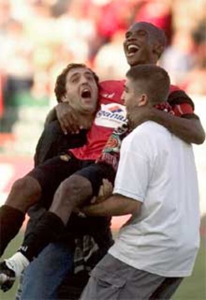 Eto'o, decisivo en la victoria del Mallorca, es manteado por dos aficionados al termino del partido.