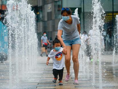 Una mujer y un niño pasean con mascarilla por un centro comercial de Pekín.
