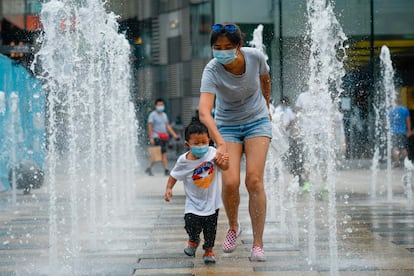 Una mujer y un niño pasean con mascarilla por un centro comercial de Pekín.