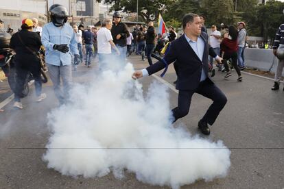 Luis Florido, deputado do partido Vontade Popular, joga uma lata de gás lacrimogêneo lançado do interior da base militar de Carlota, nesta terça-feira em Caracas.