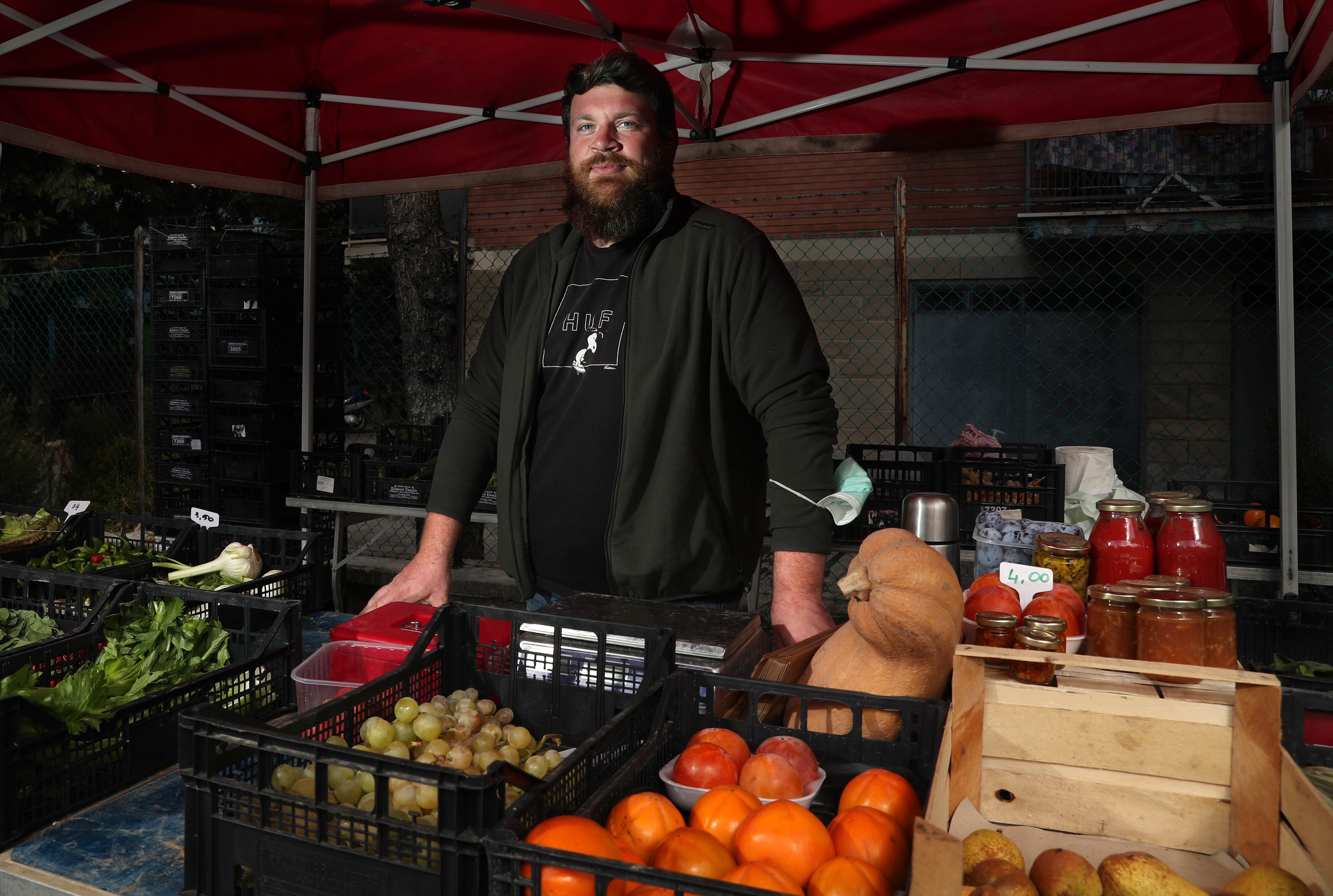 Matteo Scarpellini, dueño de la hacienda Ca' de Cesari, en su puesto de fruta y verdura en el mercado ExDazio de Bolonia.