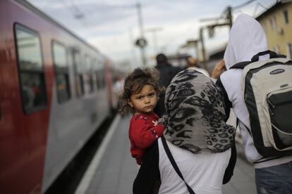 Una mujer con su hija en brazos camina por la estación de tren de la ciudad fronteriza de Passau, en Alemania.