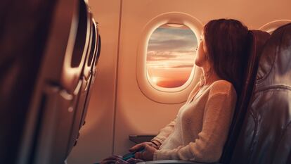 Una mujer mira por la ventana de una avión.